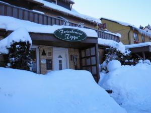 un edificio cubierto de nieve con un cartel. en Feriendomizil Tippe, en Braunlage