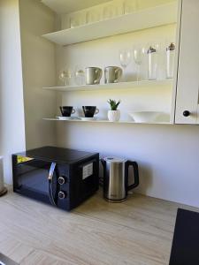 a microwave sitting on a kitchen floor with a coffee maker at Vilimiškės Apartamentai in Palanga
