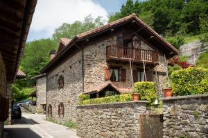 a stone house with a balcony on a street at IZURRENEA Casa Rural in Arano