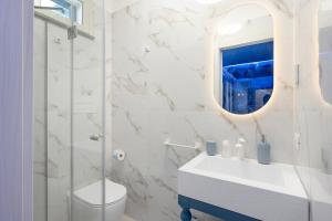 a white bathroom with a sink and a mirror at Suite Horizon Marine in San Vito lo Capo +12 photos