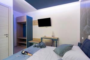 a bedroom with a bed with a tv on the wall at Suite Horizon Marine in San Vito lo Capo
