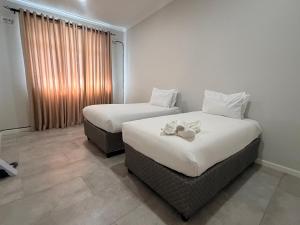 a hotel room with two beds and a window at Dreams Apartments in Victoria Falls