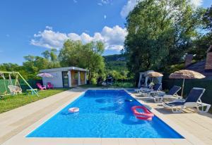 a swimming pool with chairs and a playground at Villa Lea in Bihać