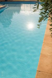 a blue swimming pool with the sun shining in the water at LA DOLOREANNE in Saint-Didier-sur-Chalaronne