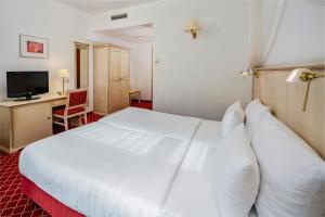 a hotel room with a white bed and a television at Hotel Chateau Berlin Kurfürstendamm in Berlin +34 photos