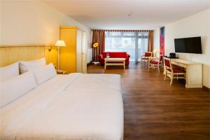 a bedroom with a large white bed and a living room at Hotel Chateau Berlin Kurfürstendamm in Berlin