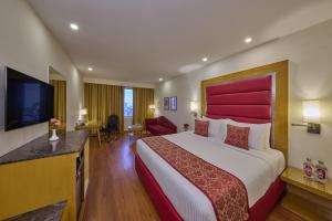 a hotel room with a large bed with a red headboard at Royal Orchid Central Bangalore, MG Road in Bangalore