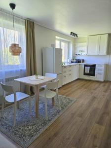 a kitchen with a table and chairs and a refrigerator at Vilimiškės Apartamentai in Palanga
