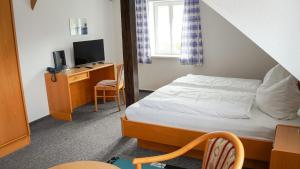 a bedroom with a bed and a desk with a television at BohnApartments Vogelmühle Ilsenburg in Ilsenburg