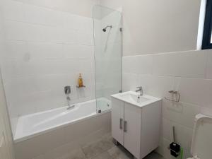 a white bathroom with a sink and a tub and a shower at Dreams Apartments in Victoria Falls +15 photos