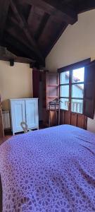 a bedroom with a large purple bed with a window at La Casuca de Pechón in Pechón