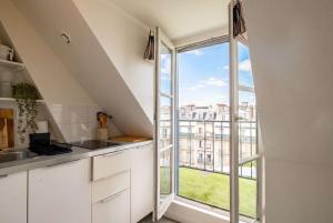 a kitchen with white cabinets and a large window at Sebastopol Chic Balcon & Parisian View in Paris