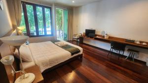 a bedroom with a bed and a desk and a window at Utime Riverside Kanchanaburi in Ban Yang (2)