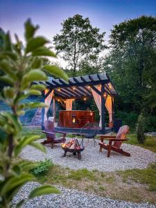 a gazebo with two benches and a fire pit at ACASĂ la Lisa in Lissa