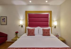 a bedroom with a large bed with a red headboard at Royal Orchid Central Bangalore, MG Road in Bangalore