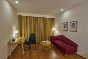 a living room with a red couch and a desk at Royal Orchid Central Bangalore, MG Road in Bangalore