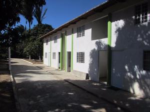 ein weißes Gebäude mit grünen Türen und einem Gehweg in der Unterkunft Pousada Sitio Costa Verde in Ubajara