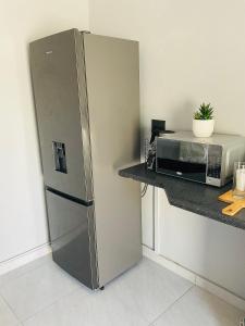 a stainless steel refrigerator in a kitchen next to a microwave at Koshoka Home in Ompanda