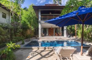 a house with a swimming pool with a blue umbrella at Plataran Komodo Resort & Spa - CHSE Certified in Labuan Bajo