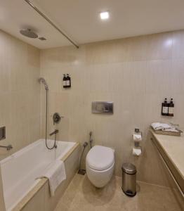 a bathroom with a toilet and a tub and a sink at Royal Orchid Central Bangalore, MG Road in Bangalore