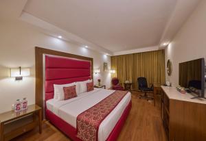 a hotel room with a large bed with a red headboard at Royal Orchid Central Bangalore, MG Road in Bangalore +23 photos