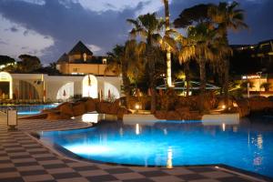 a pool at night with palm trees and a building at Pine Beach Belek in Belek