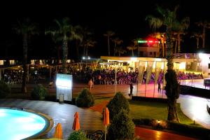 a group of people standing around a pool at night at Pine Beach Belek in Belek +244 photos