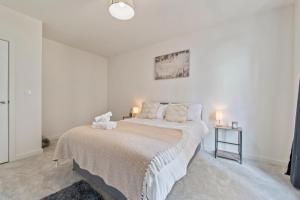 a white bedroom with a bed and two lamps at Stylish 1-Bed flat with Private Balcony in Hatch End