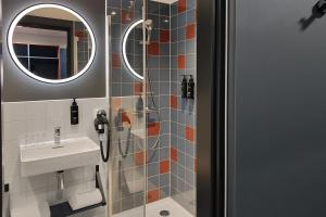 a bathroom with a shower with a sink and a mirror at the niu Clink in Hamburg +39 photos