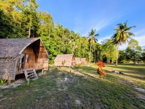 a group of buildings in a field with palm trees at Tanjung Kalemo Resort in Batudaka