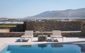 two chairs and a table next to a swimming pool at Alkinoe Villa Paros in Isterni