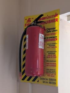 a red fire extinguisher hanging on a wall at Sona Rooms in Tiruchirappalli +4 photos