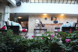 a waiting area with chairs and flowers in a lobby at Hotel Palace Inn SCLC in San Cristóbal de Las Casas