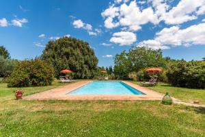 a swimming pool in a yard with two umbrellas at Tenuta Bichi Borghesi in Monteriggioni