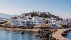 a group of white houses on a hill next to the water at Lagos Mare Hotel in Agios Prokopios