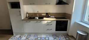a kitchen with white cabinets and a sink and a stove at Le Logis du Donjon 1 in Les Herbiers