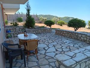 a patio with a table and chairs and a stone wall at Kalivakia View in Tsoukalades