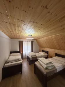 three beds in a room with a wooden ceiling at Guesthouse Alpini in Lëpushë