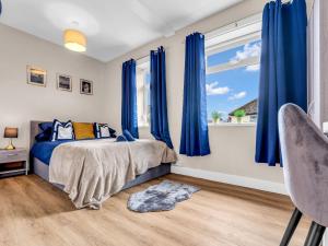 a bedroom with blue curtains and a bed and a window at LetSavvy Contractor Accommodation Hartlepool in Hartlepool