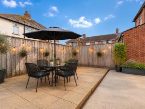 a patio with a table with chairs and an umbrella at LetSavvy Contractor Accommodation Hartlepool in Hartlepool