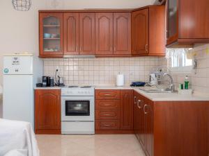 a kitchen with wooden cabinets and a white stove top oven at Nice & Cosy apartment in Igoumenitsa in Igoumenitsa