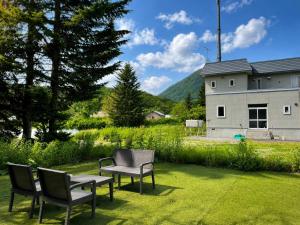 a patio with chairs and a table and a house at Japow KiichiGo! in Kimobetsu