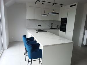a kitchen with a white counter and blue chairs at Chez nous a Durbuy in Durbuy