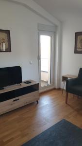 a living room with a flat screen tv and a table at Apt Moravica in Soko Banja