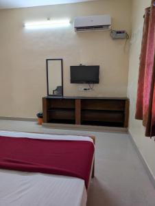 a room with two beds and a flat screen tv at Sona Rooms in Tiruchirappalli