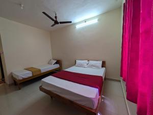 two beds in a room with pink curtains at Sona Rooms in Tiruchirappalli