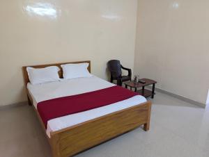 a bedroom with a bed with a chair and a table at Sona Rooms in Tiruchirappalli