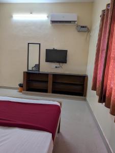 a room with a tv on a wall with a bed at Sona Rooms in Tiruchirappalli