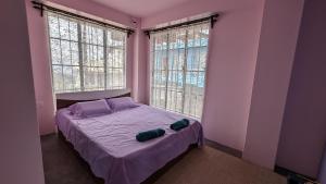 a bedroom with a bed with purple sheets and two windows at GRETZbnb in Shillong +30 photos