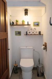 a bathroom with a toilet and shelves on the wall at Tite Case Désirée in Petite Île